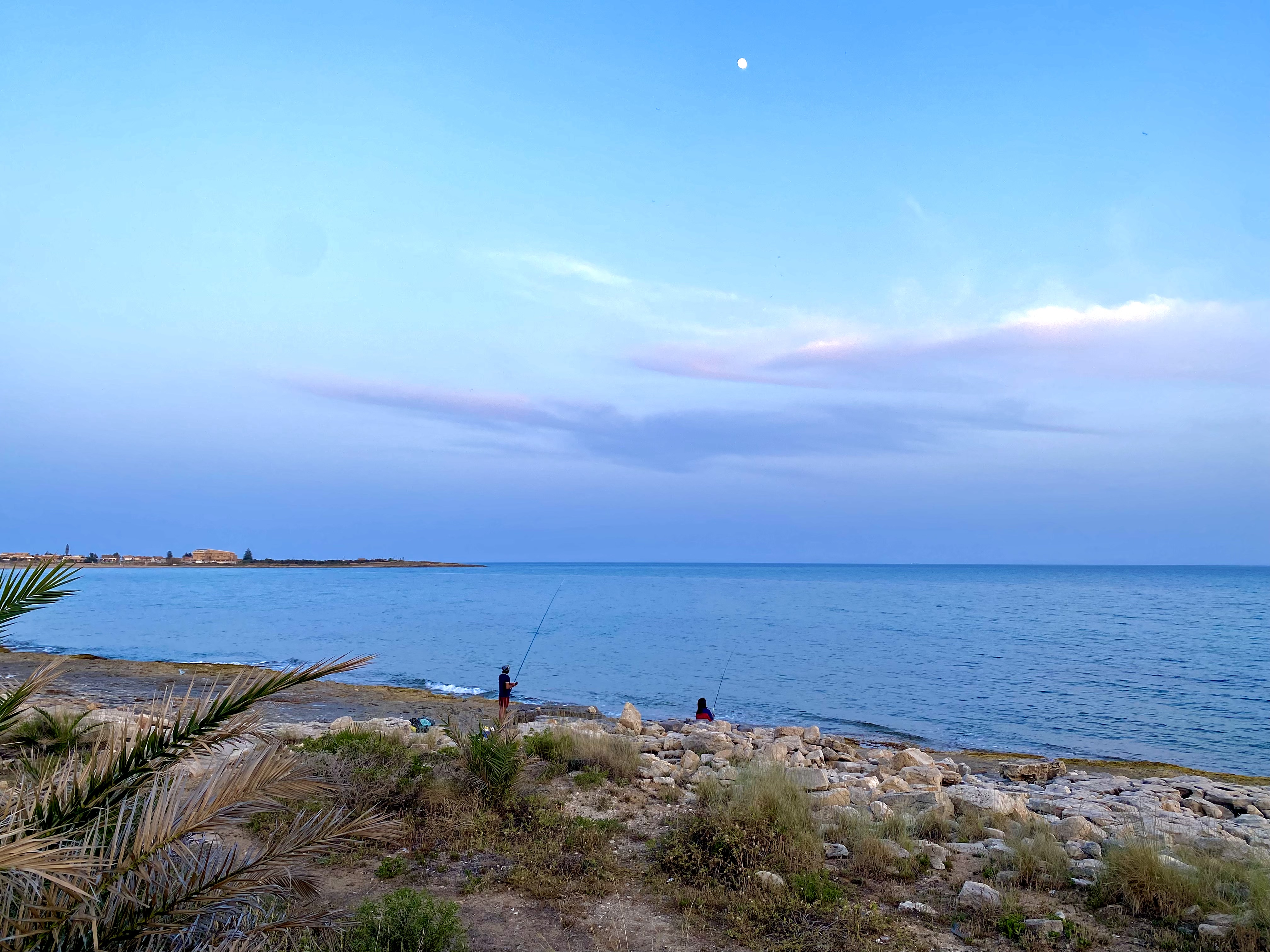 Pescatori al tramonto sulla scogliera di Marina di Modica con la luna